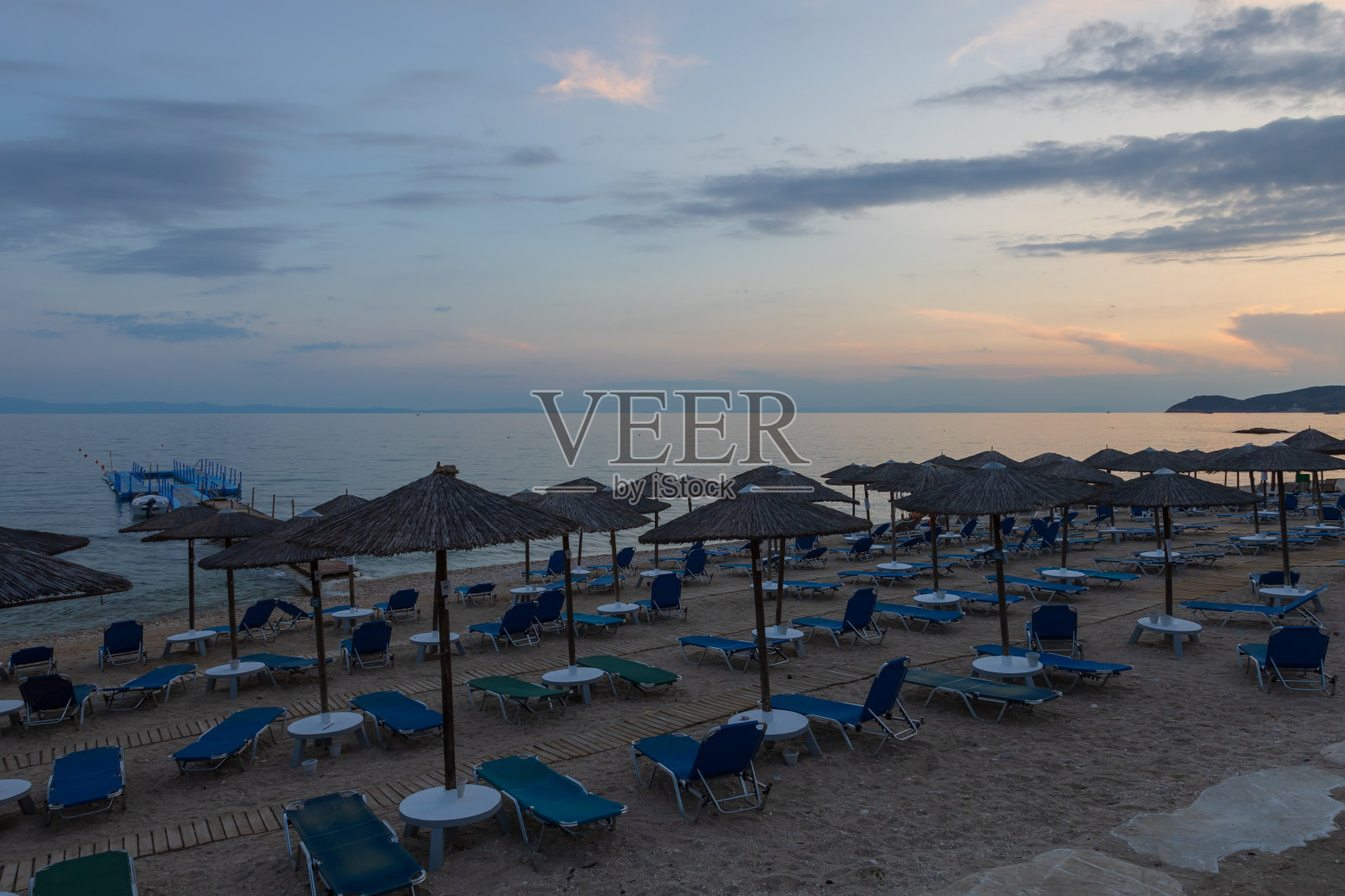 希腊塔索斯岛的傍晚酒店海滩。海滩上有雨伞和日光浴床。照片摄影图片