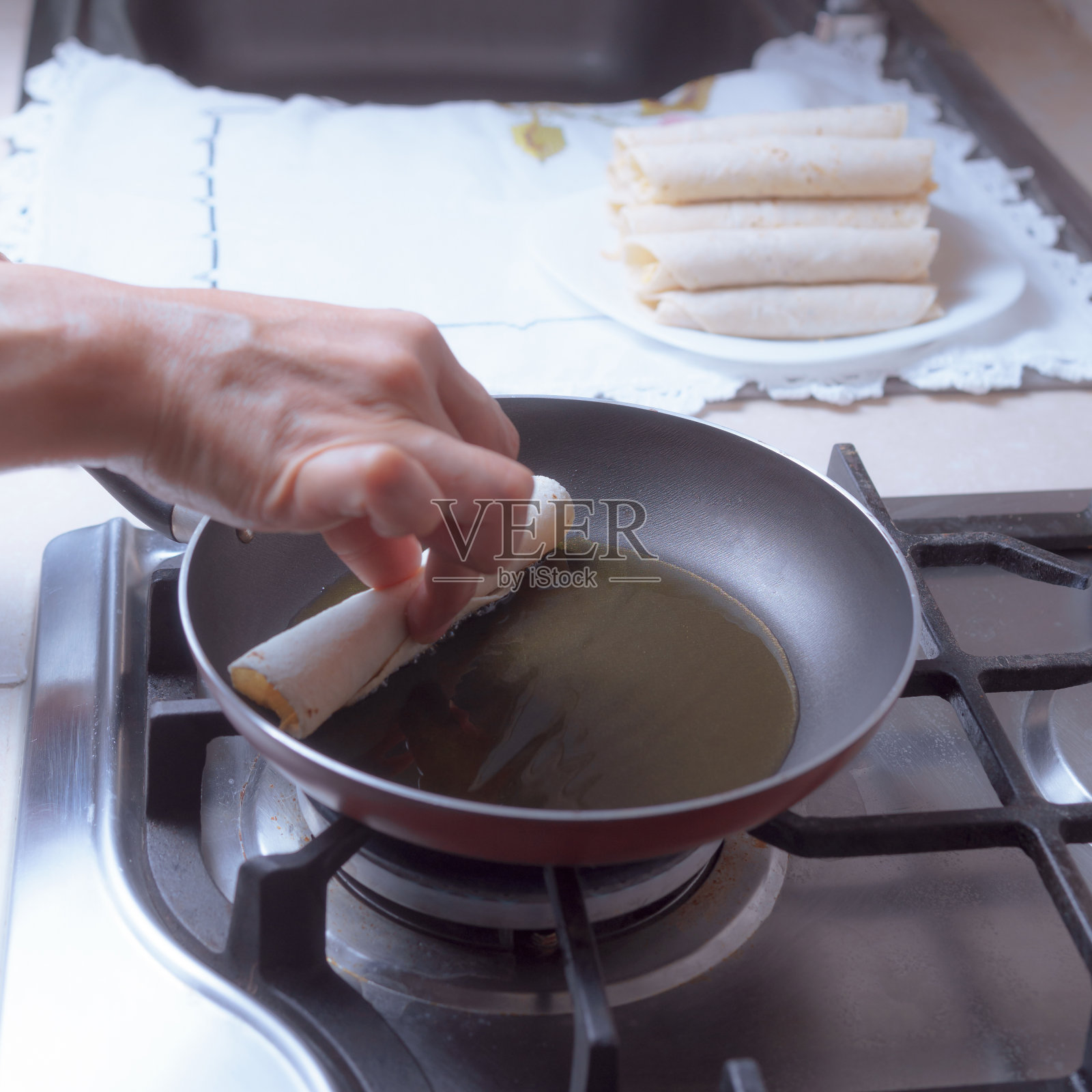 准备煎玉米饼在煎锅里,只看到一些手把一些玉米饼在锅里。照片摄影图片