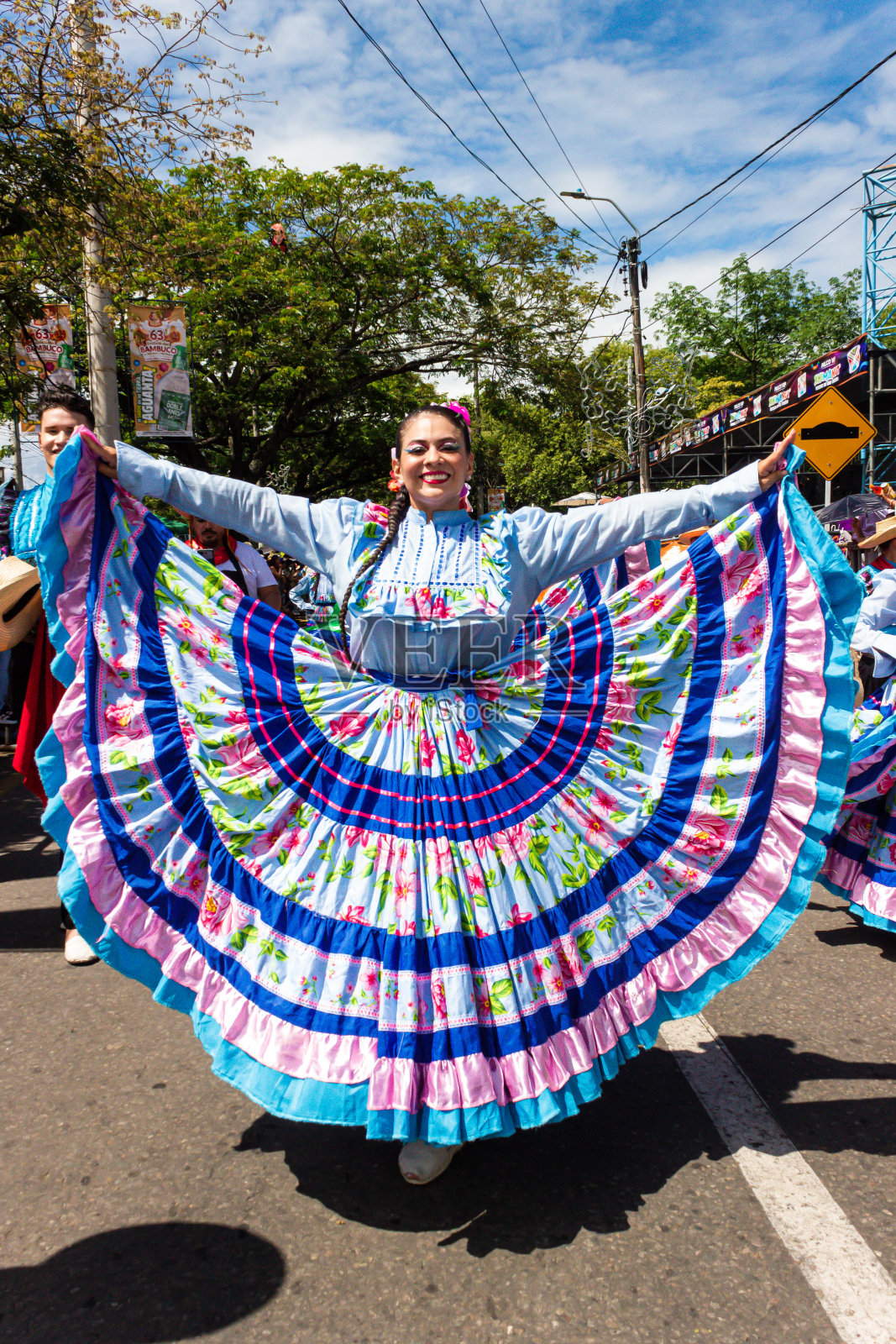 一名身着传统蓝色服装的拉丁裔妇女在游行中微笑着看着镜头照片摄影图片