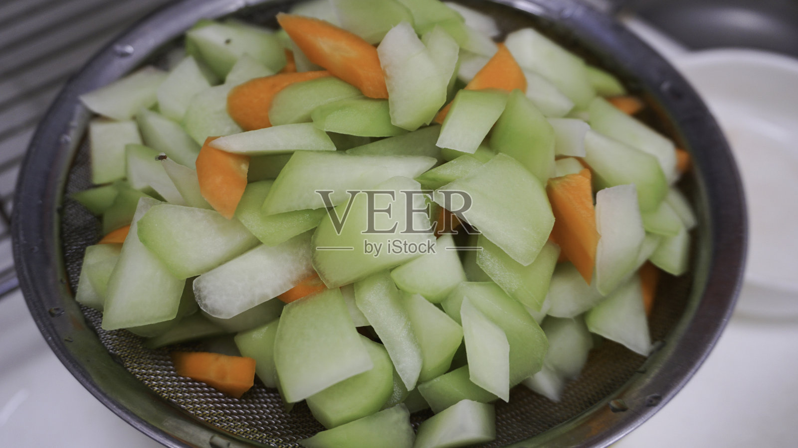 将佛手瓜和胡萝卜片放入滤锅中照片摄影图片