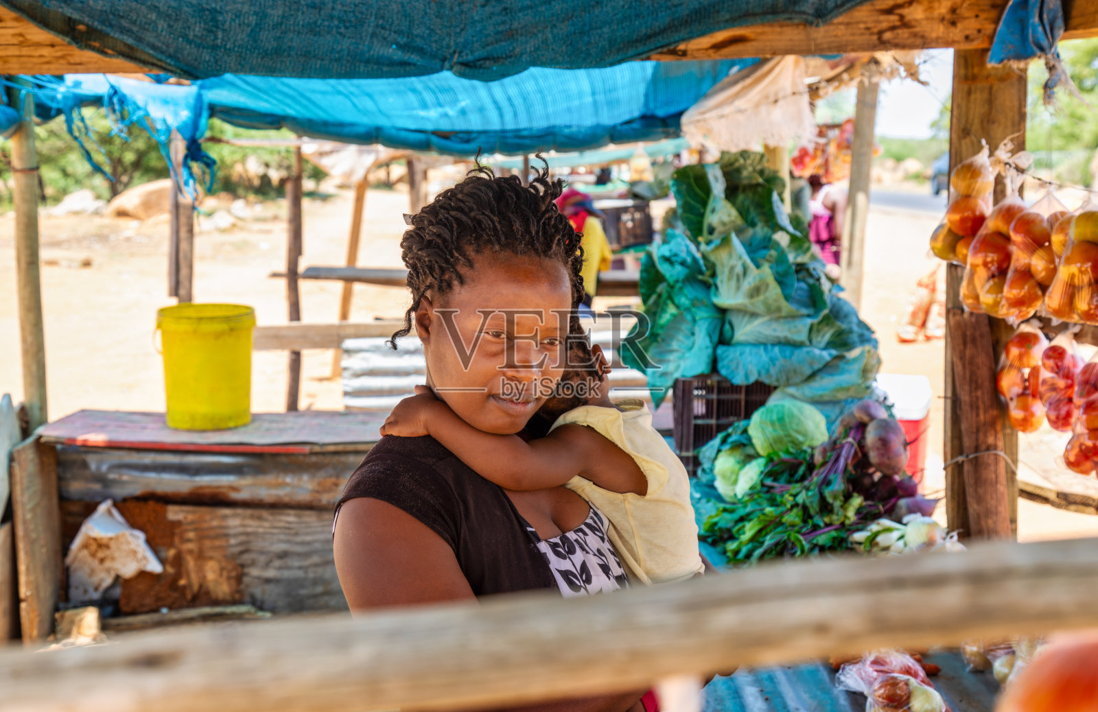 非洲乡村街头小贩,母亲抱着她的女儿,两人都扎着辫子,照片摄影图片
