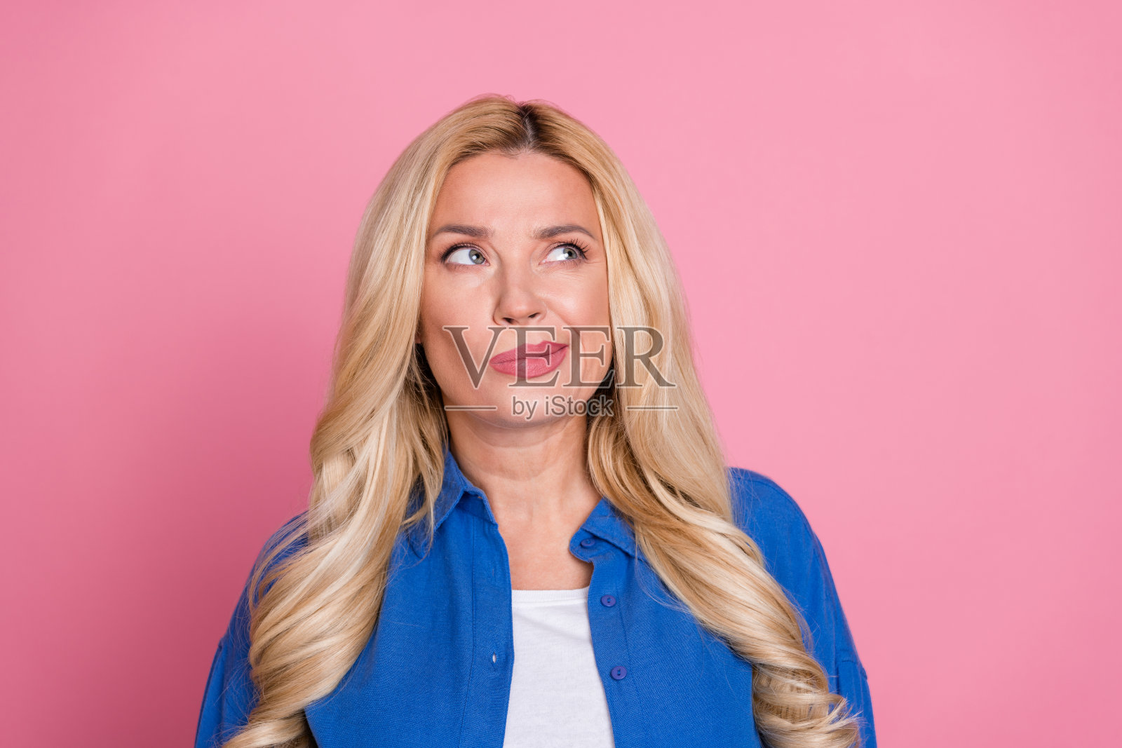 照片中可疑的漂亮女士穿着蓝色夹克,看起来空无一物,孤立的粉红色背景照片摄影图片