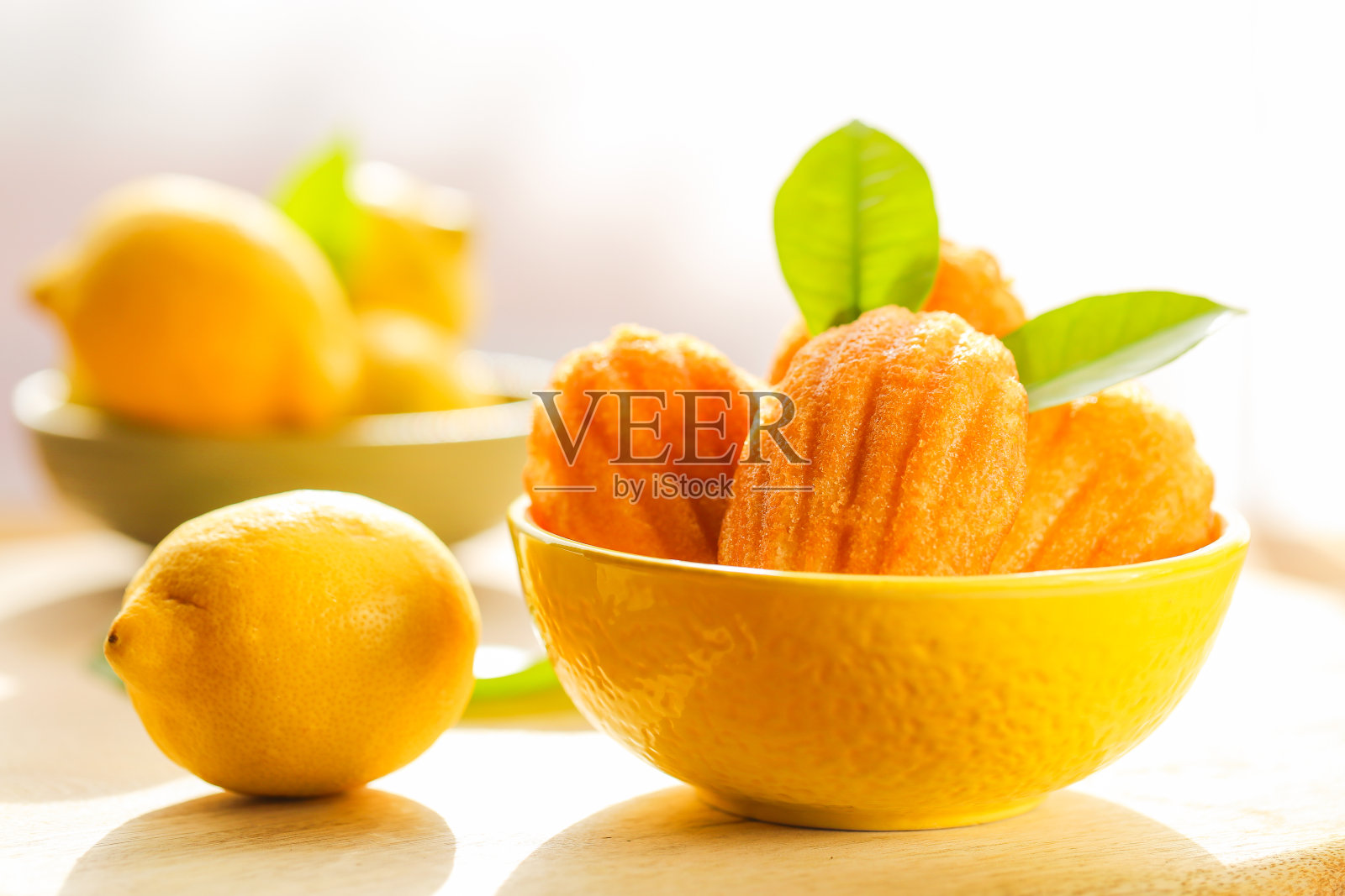 玛德琳饼干。玛德琳饼干饼干。法式甜点。柠檬法国饼干和柠檬水果在明亮的阳光下特写。法式玛德琳饼干照片摄影图片