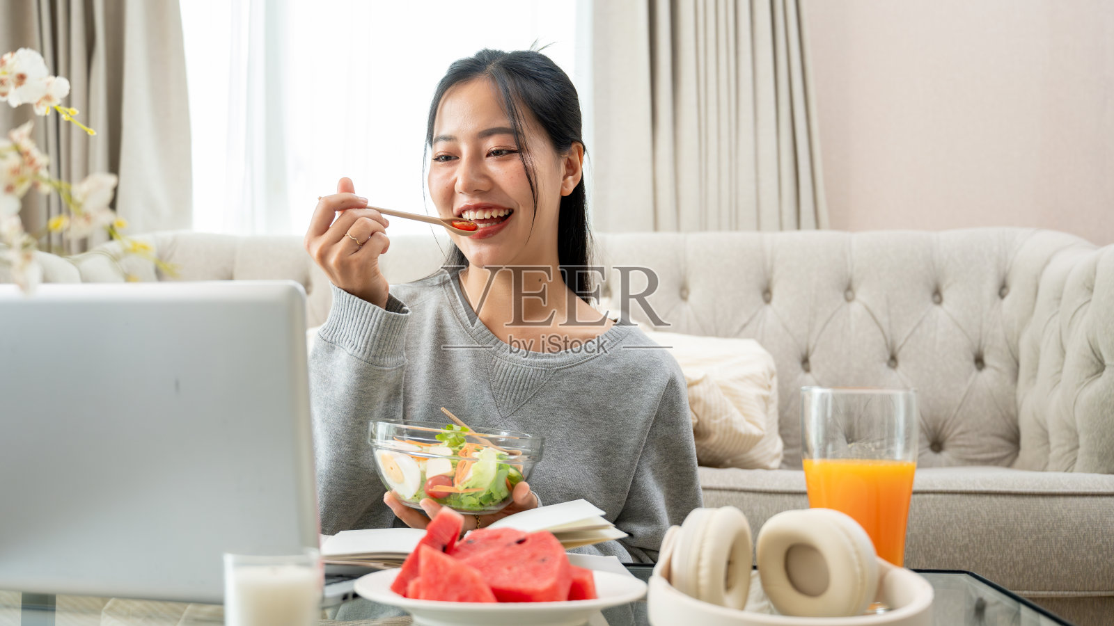 一位女士一边吃早餐,一边在咖啡桌上用笔记本电脑工作或在线学习。照片摄影图片