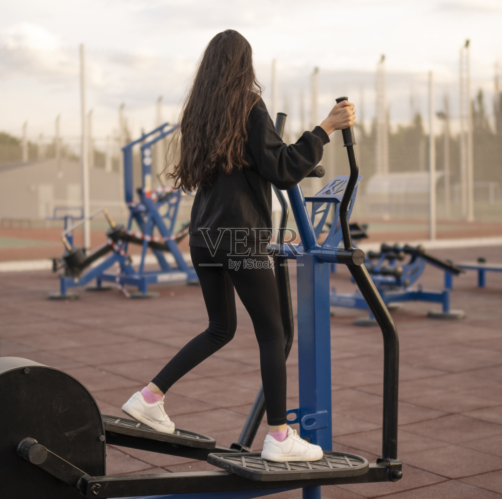 女运动员在室外椭圆机上进行腿部训练照片摄影图片
