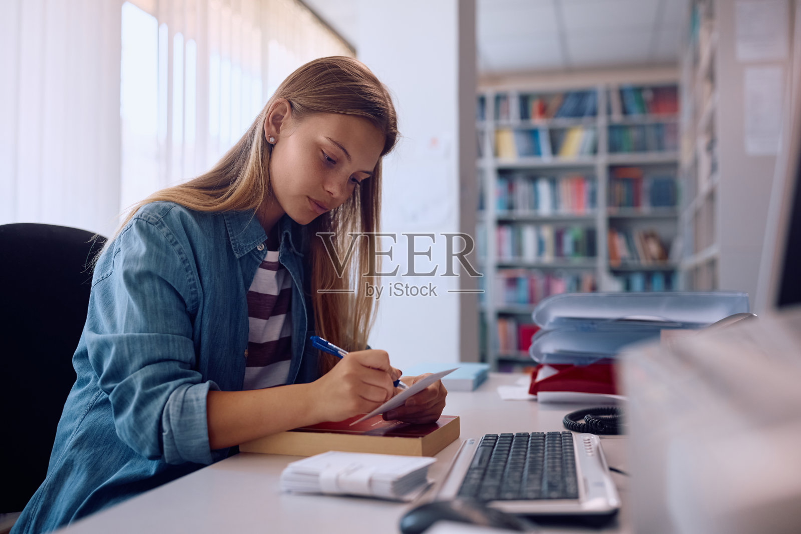在大学图书馆学习的年轻女子。照片摄影图片