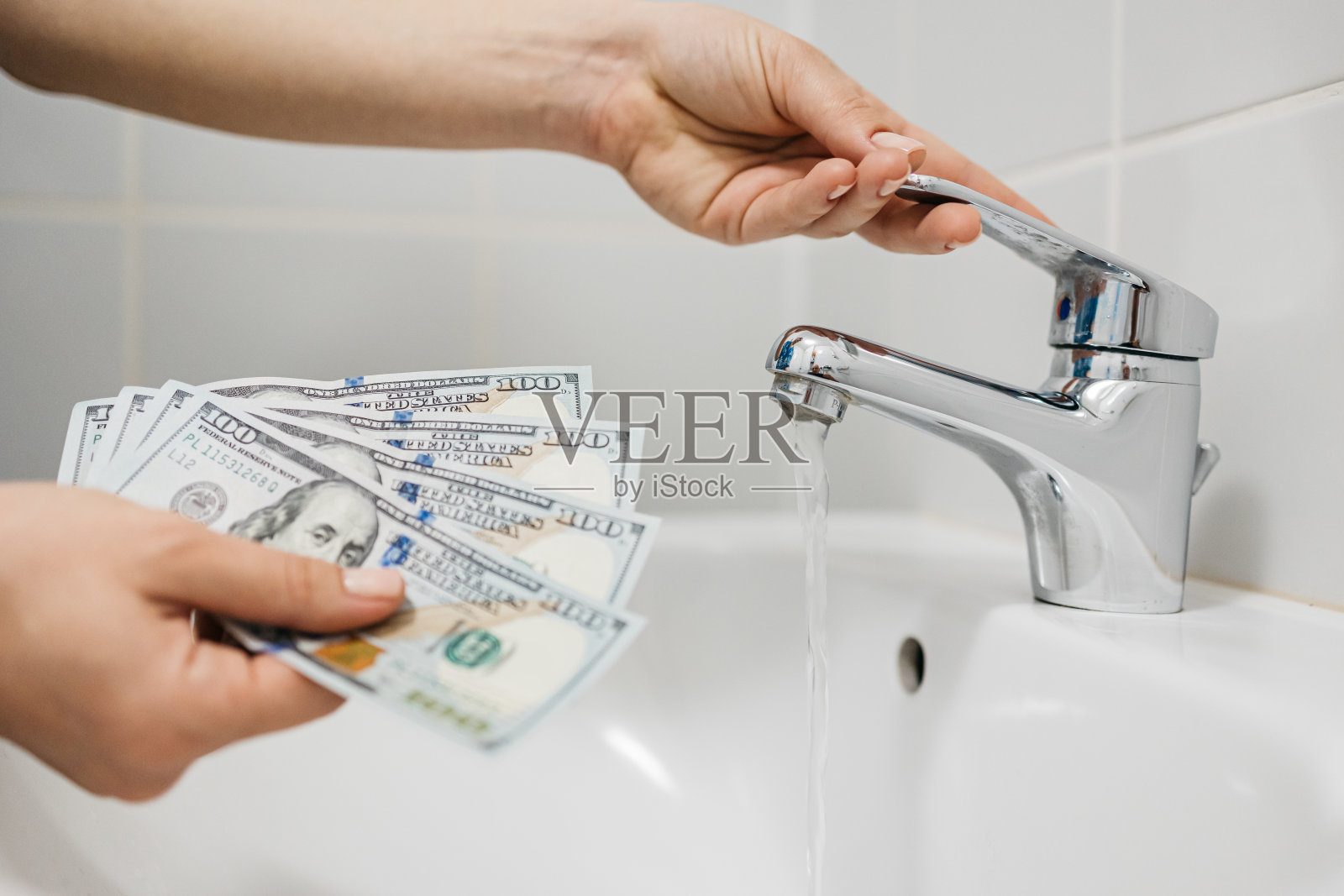 女人在家里用手关掉水龙头,数着省下的钱。节约资源和水电费的概念。照片摄影图片