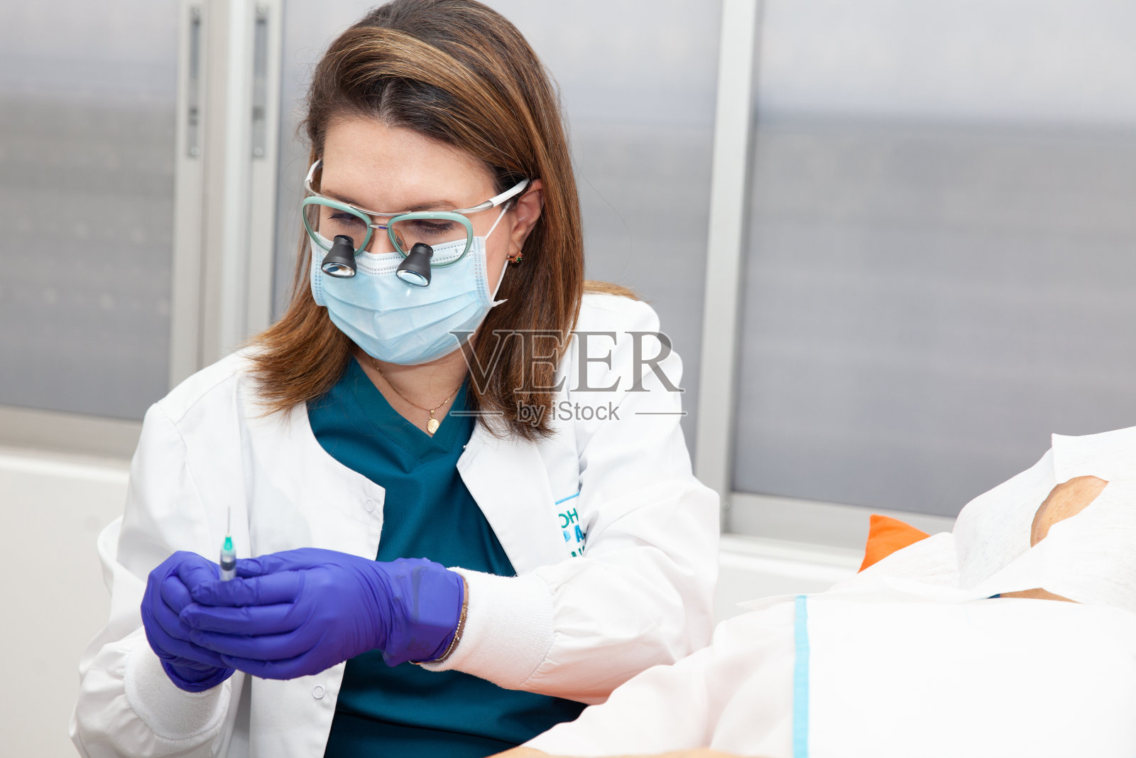 皮肤科医生正在对一位老年成人患者的面部进行皮肤活检。麻醉的应用。照片摄影图片