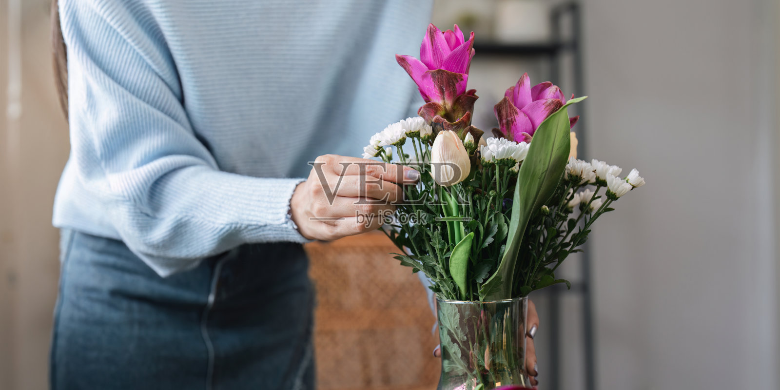 女人在家里的花瓶里插花,在一个舒适的生活空间里创造一个美丽的花卉展示照片摄影图片
