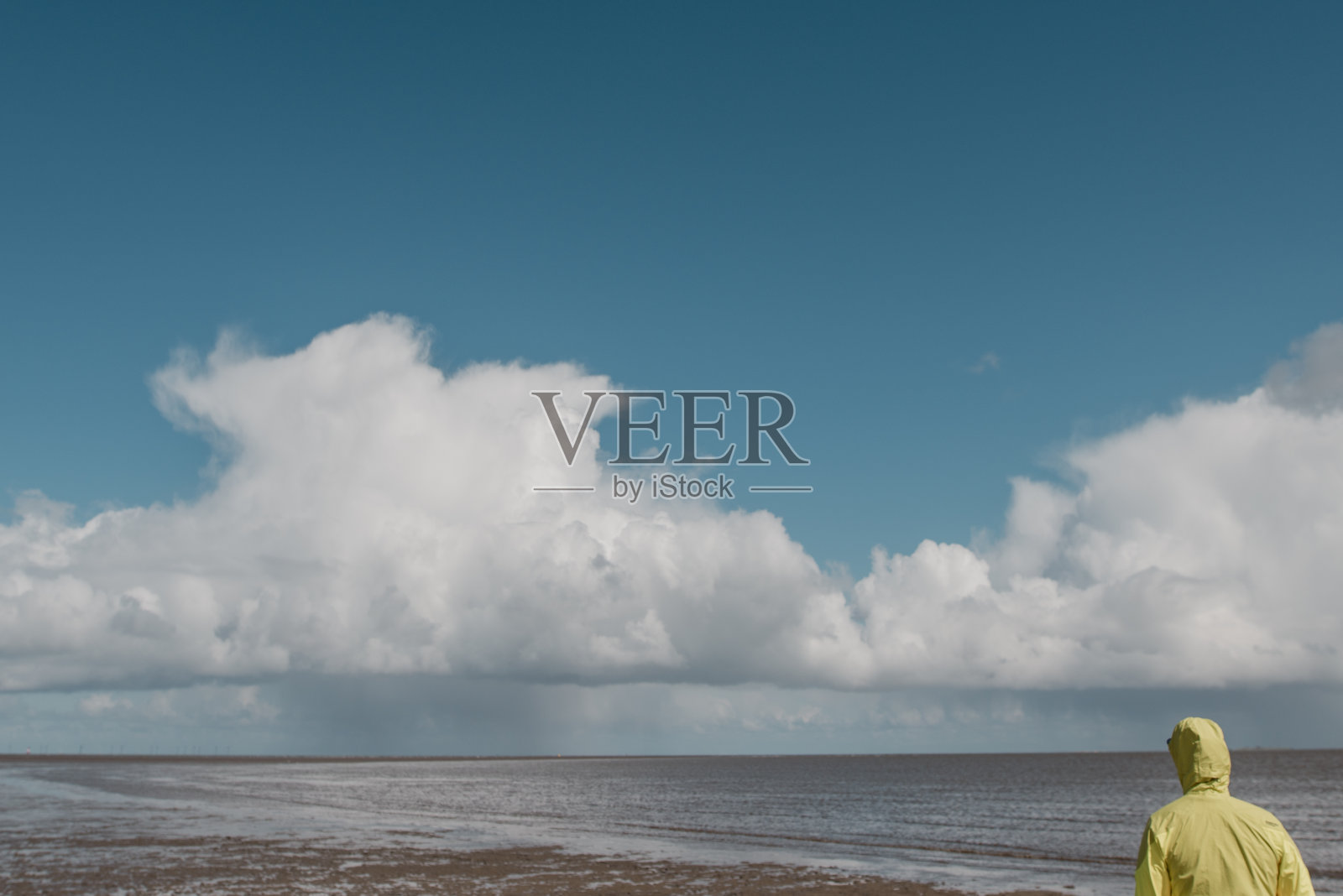 一个穿着黄色雨衣的人看着岛上的雨云照片摄影图片