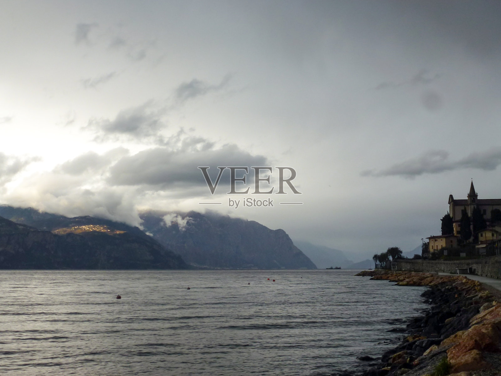 傍晚的海湾和堤岸的度假小镇,以山脉为背景照片摄影图片