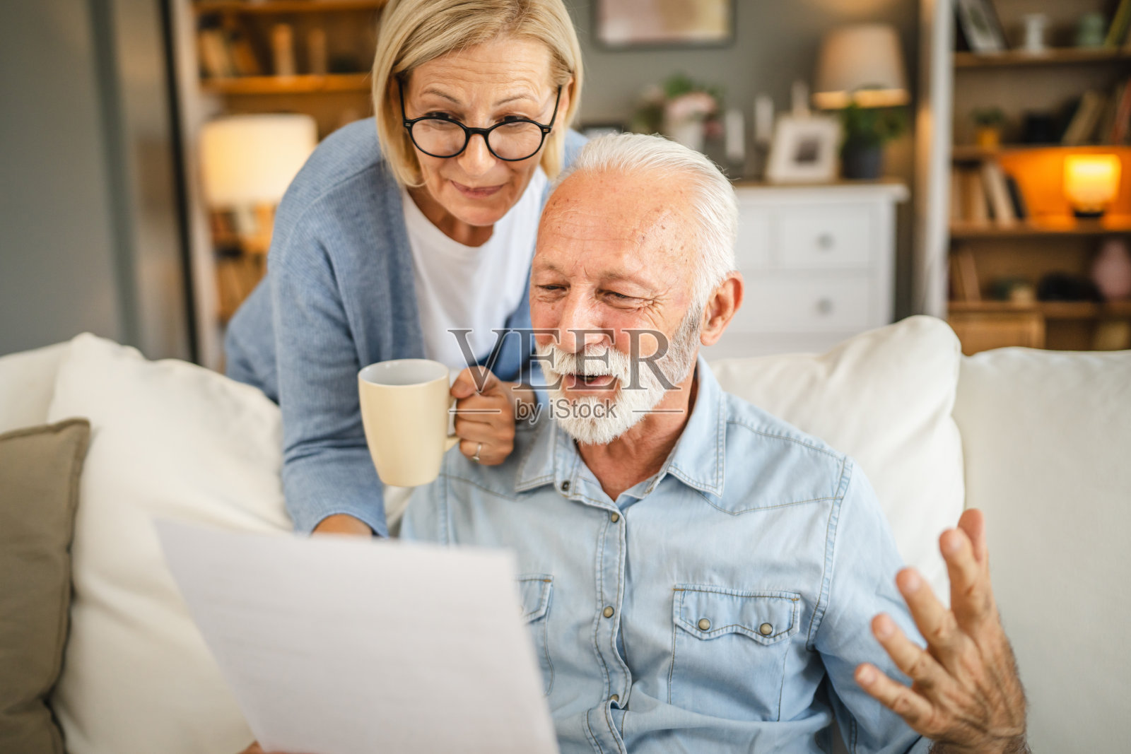 老夫妇在家里一起读信封里的信照片摄影图片