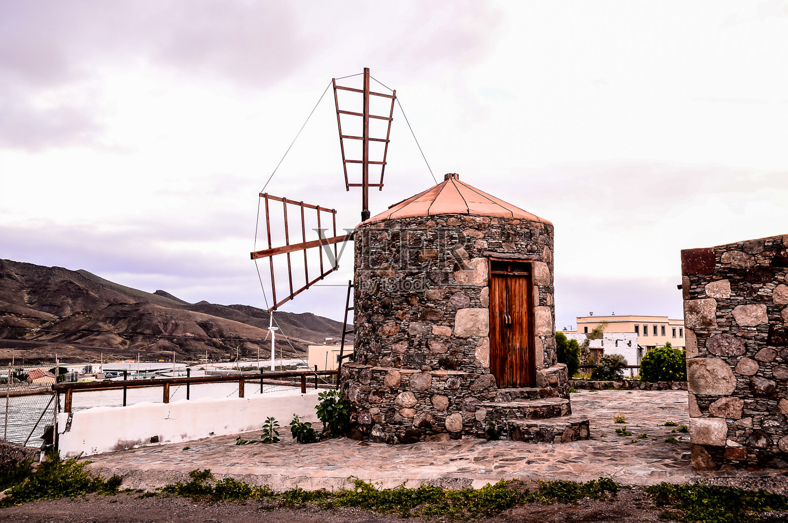 一座风车矗立在一座建筑物的前面照片摄影图片