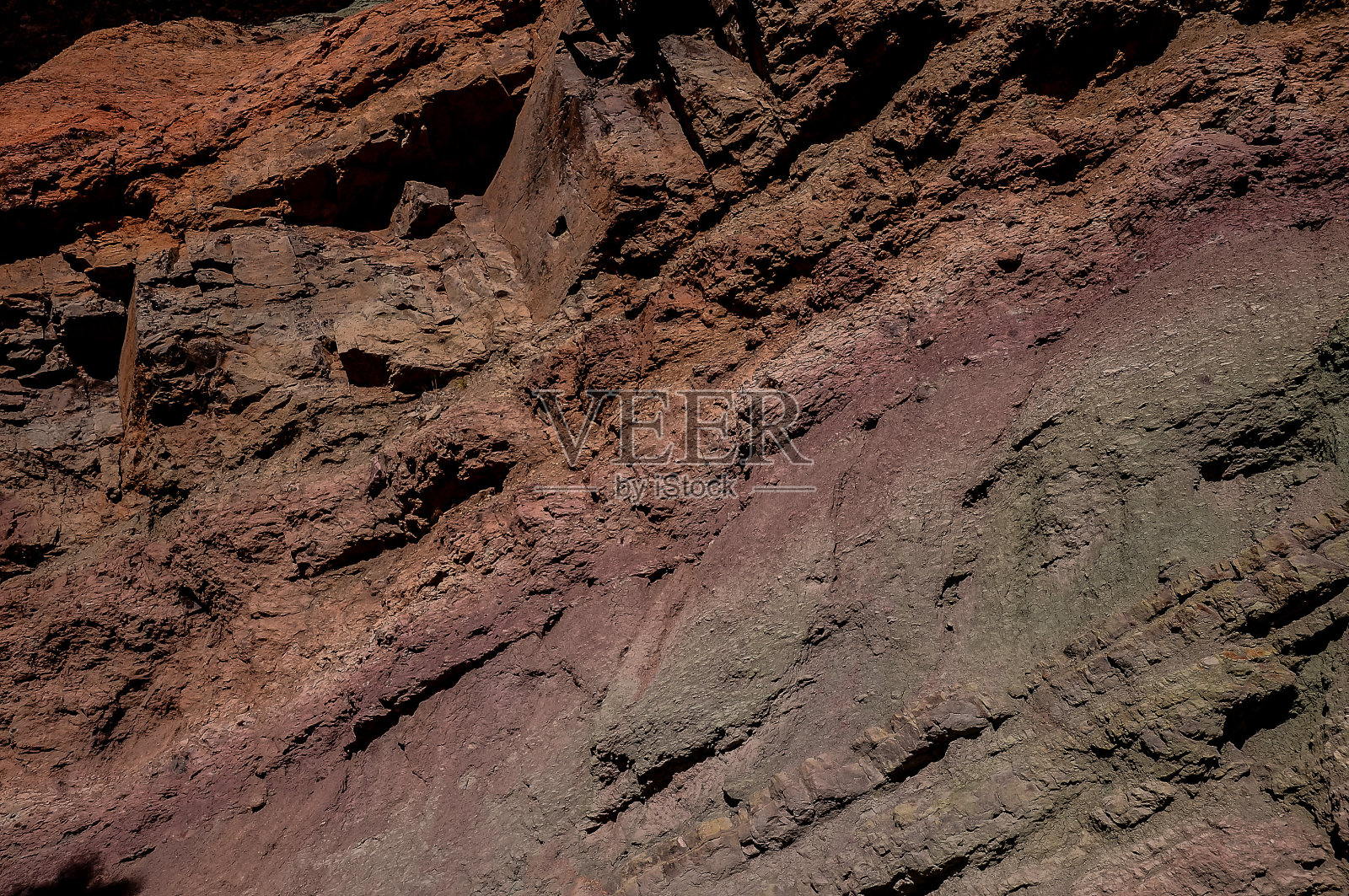 岩石表面有多种颜色的岩石表面,包括棕色、绿色和红色照片摄影图片