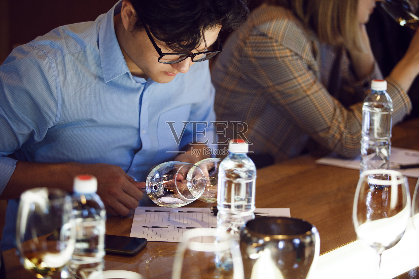 参加侍酒师品酒会的男子在餐桌上分析白葡萄酒照片摄影图片