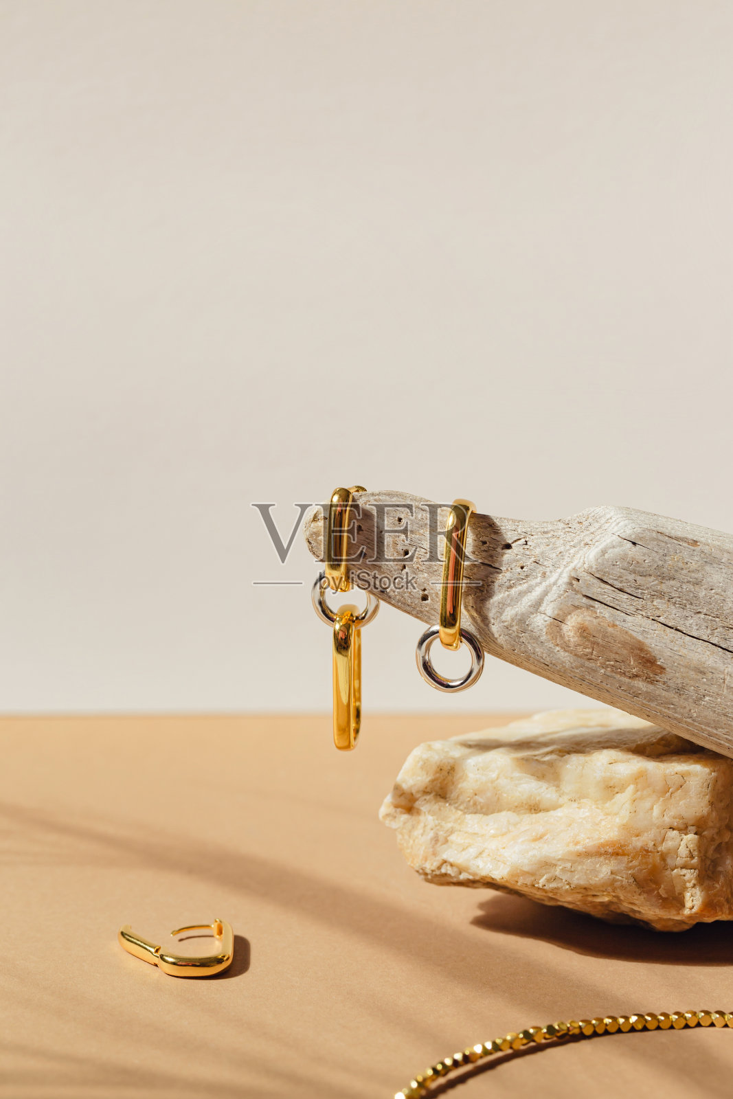 淡米色背景上的金色耳环。时尚珠宝套装照片摄影图片