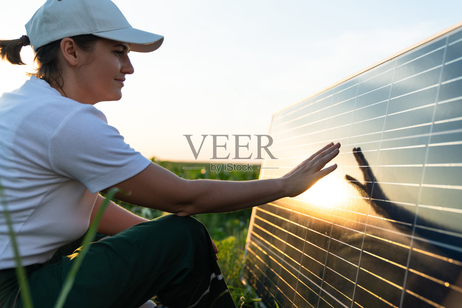 一名妇女在日落时分触摸太阳能电池板照片摄影图片