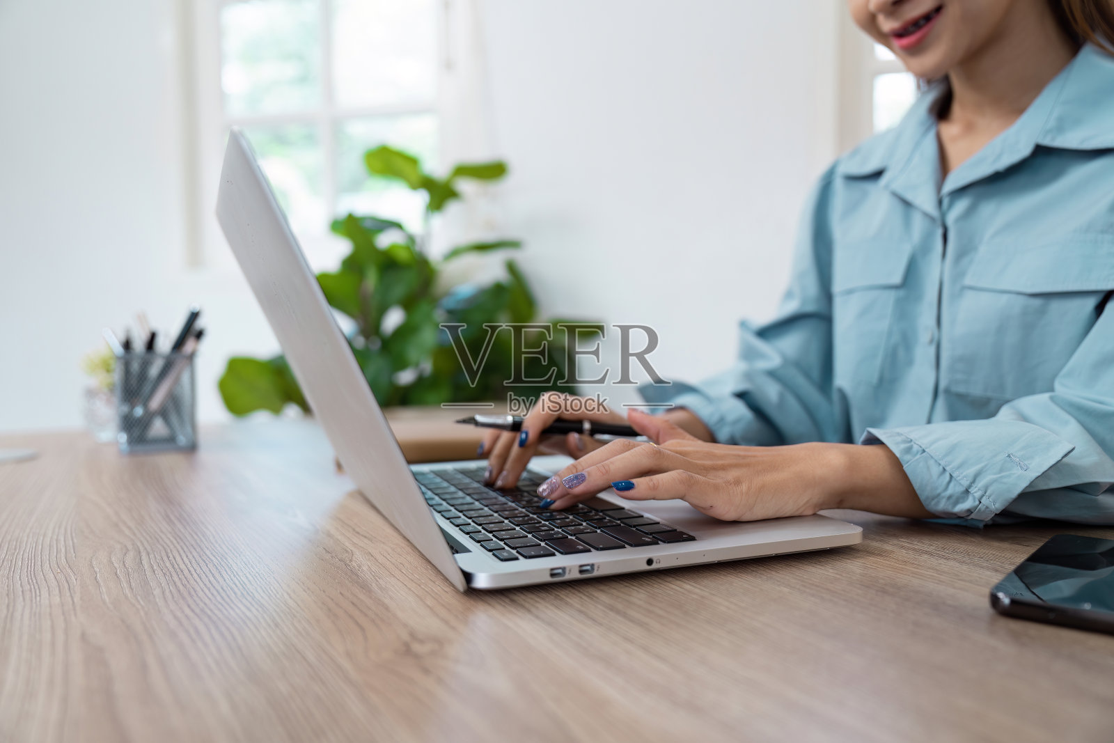 在自然光和绿色的现代家庭办公环境中,年轻的专业人士在笔记本电脑上工作照片摄影图片