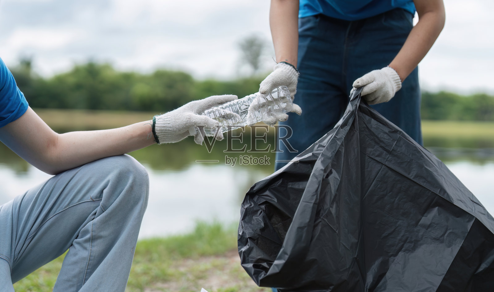 志愿者夫妇在湖边收集户外垃圾,环境清理工作,社区服务,生态友好倡议照片摄影图片