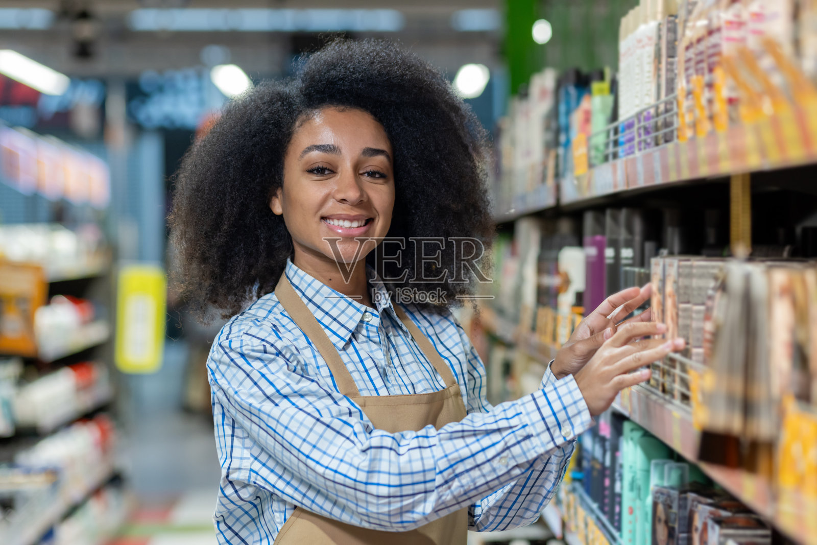 微笑的女员工在超市整理货架上的产品照片摄影图片