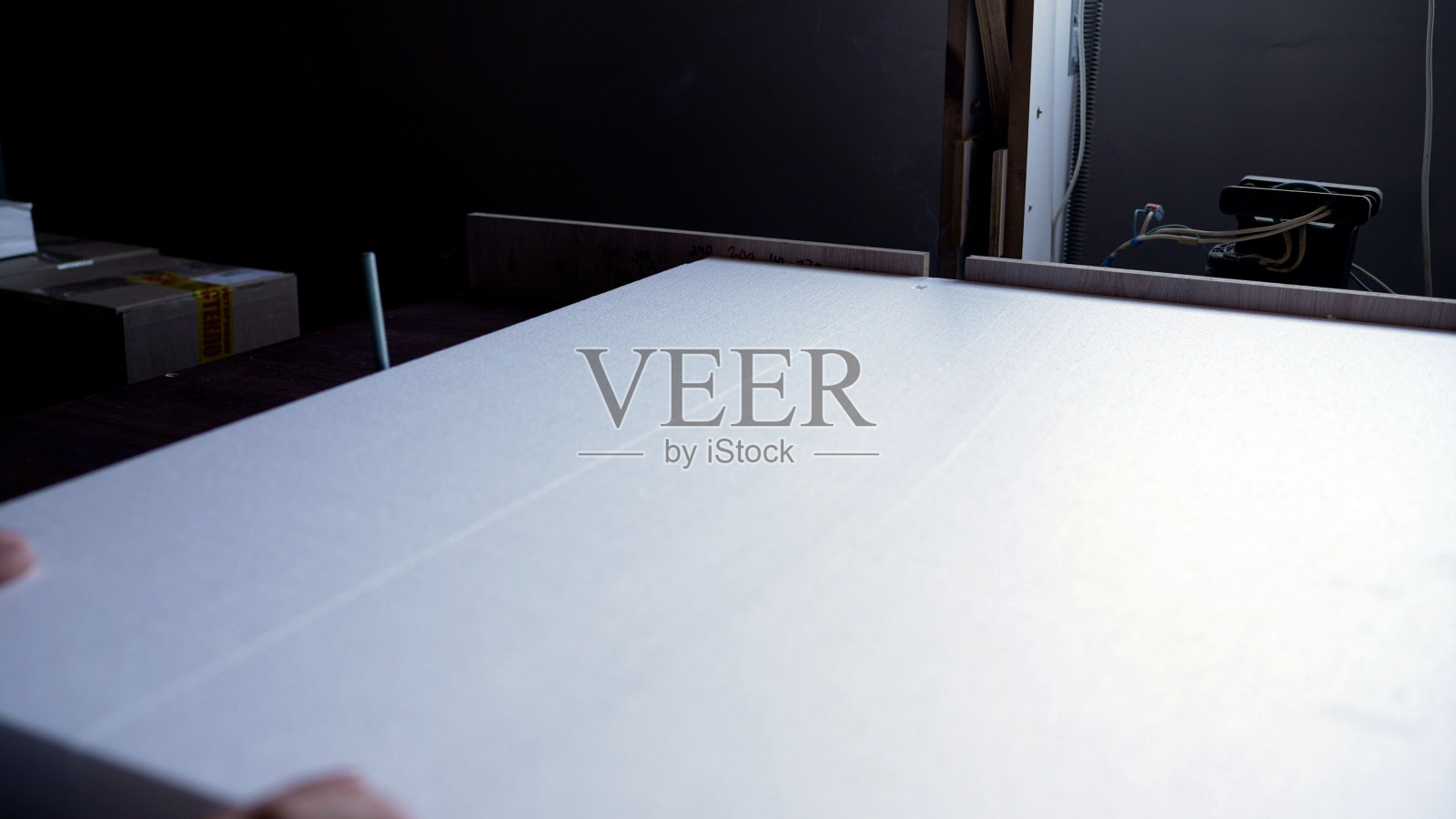 一块白色的泡沫塑料被热丝切开。聚苯乙烯泡沫是用热丝切割的。切割泡沫塑料包装的货物。照片摄影图片