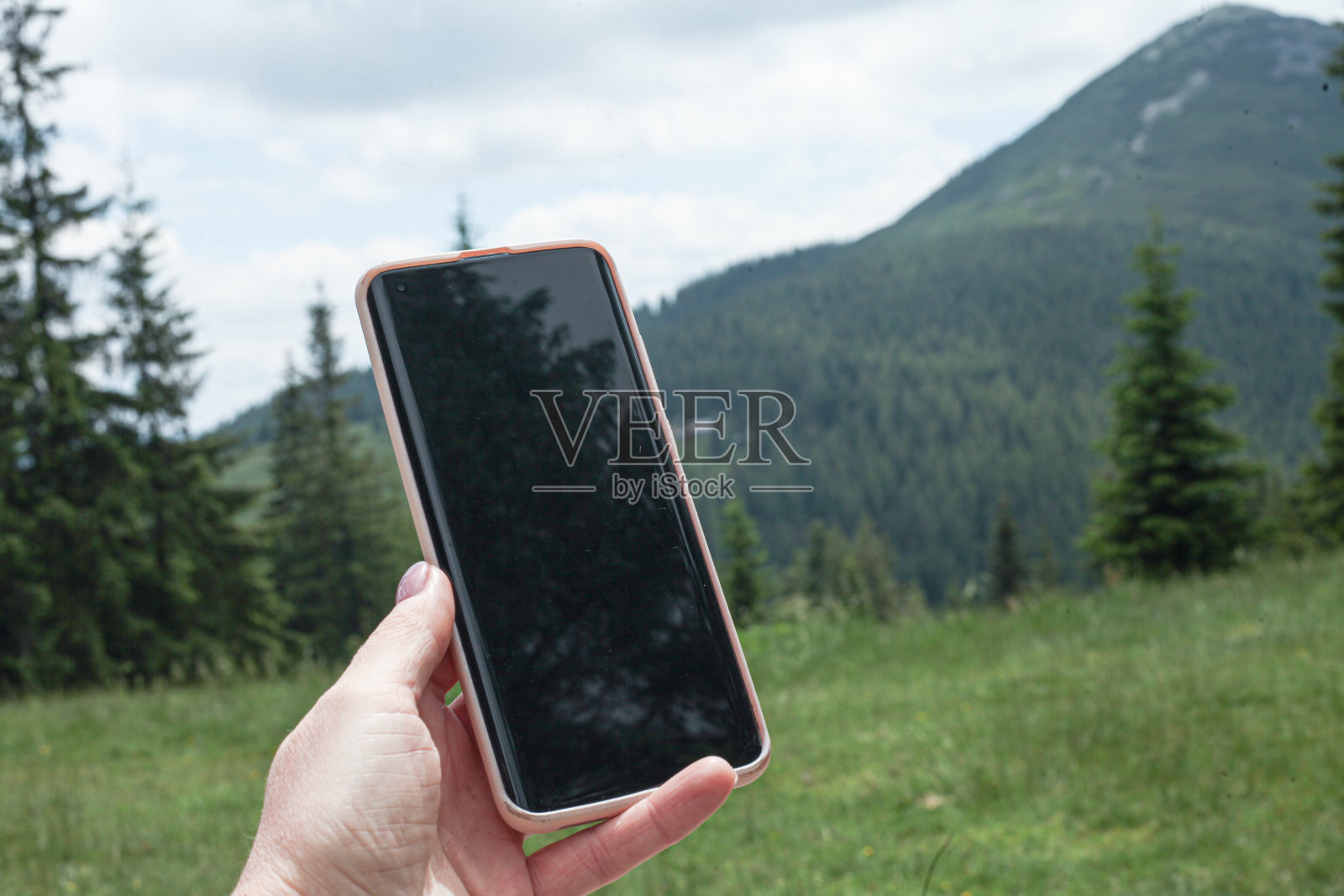 女孩手中的手机以山为背景照片摄影图片