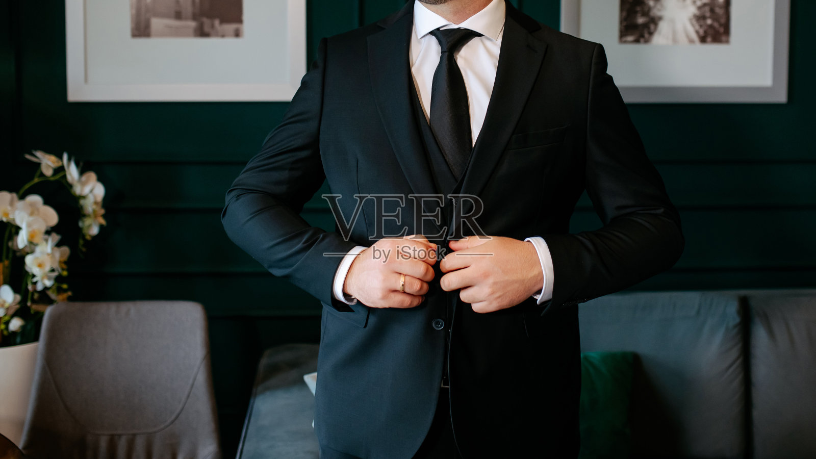 穿着优雅无尾礼服的新郎正在整理他的夹克。照片摄影图片