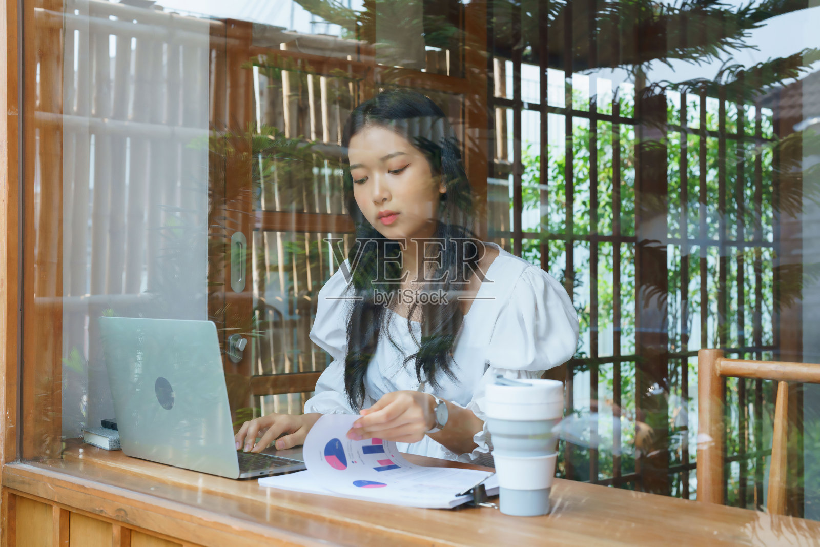 年轻的亚洲女商人一边在文件上查看企业的营销数据,一边在笔记本电脑上输入键盘数据,一边考虑在咖啡馆工作的新创业项目的投资和规划照片摄影图片