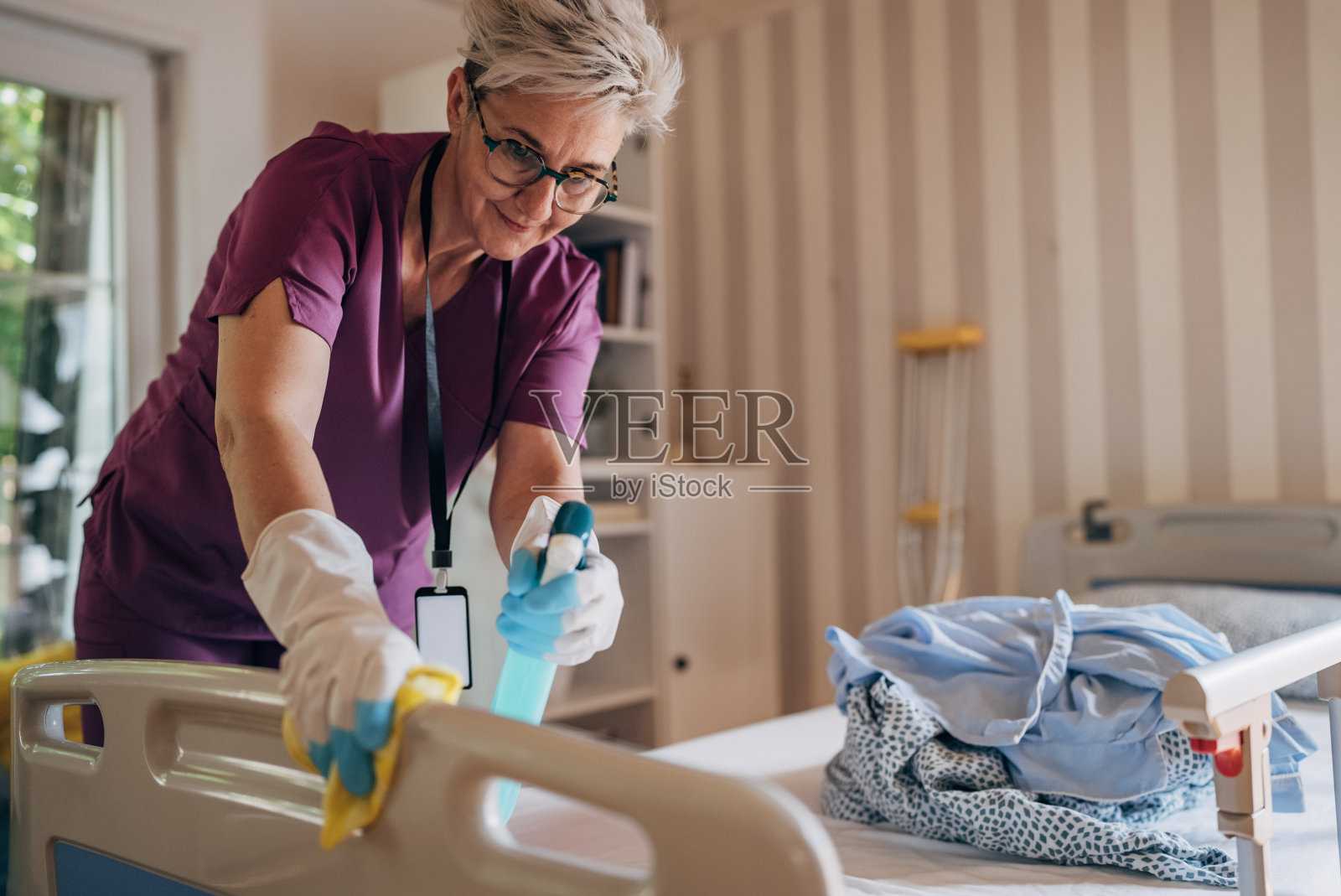 护士小心地在医院床架上喷洒消毒剂照片摄影图片