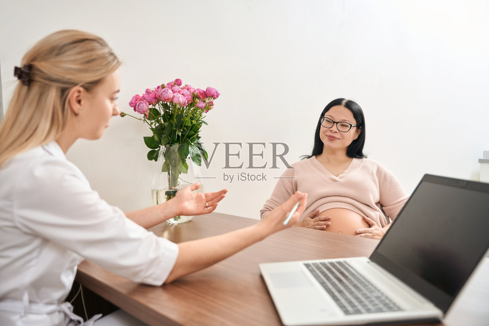 年轻女子与孕妇讨论婴儿的条件和大小照片摄影图片