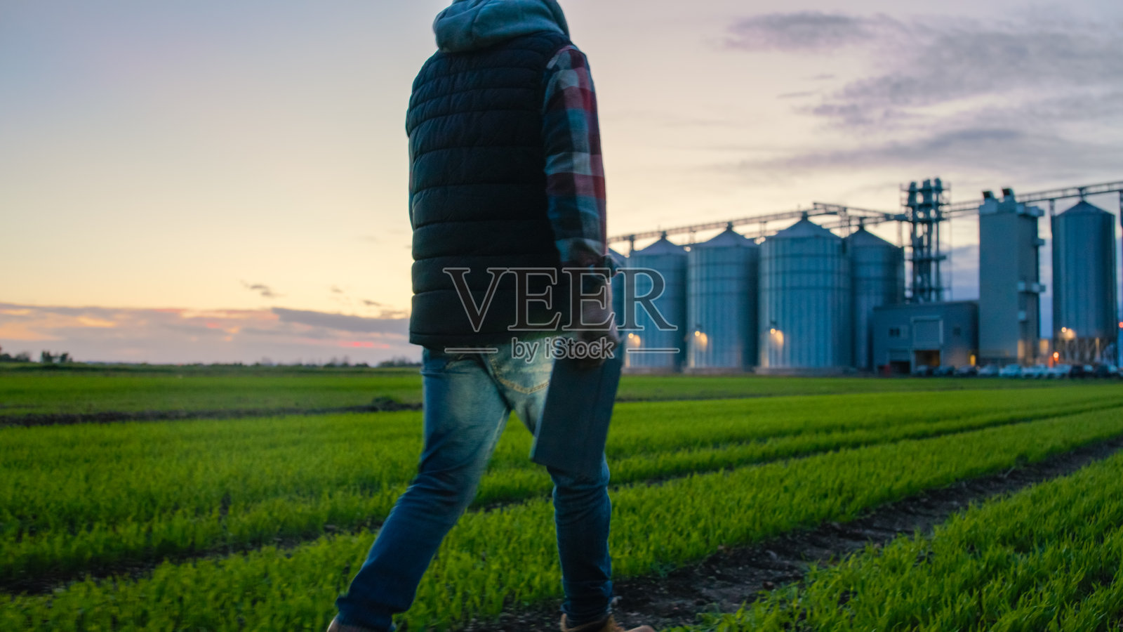 白人农民手持平板电脑俯瞰日落时分的麦田照片摄影图片