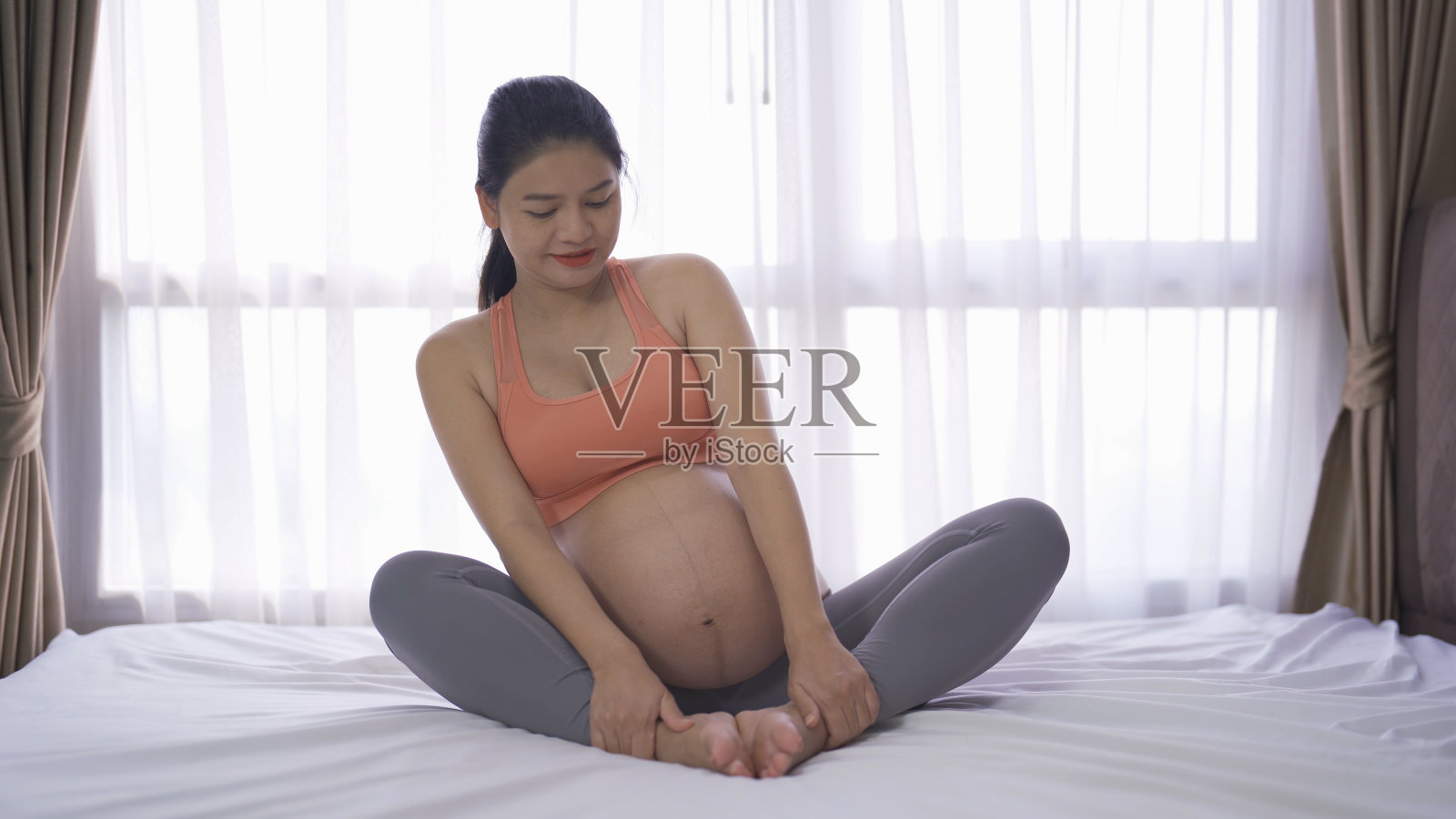 幸福的亚洲孕妇在家里卧室的肖像。生孩子了。培训锻炼。在室内用运动器材锻炼。运动。家庭人的生活方式。妈妈的爱。娱乐。照片摄影图片