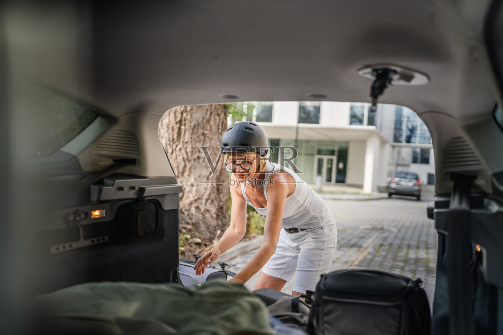 成熟的金发女子旅行时从汽车后座拿东西照片摄影图片