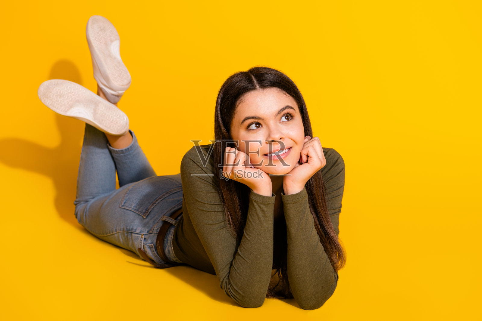 照片中,漂亮的少女露出v字舌头,穿着黄色背景的时髦卡其布服装照片摄影图片