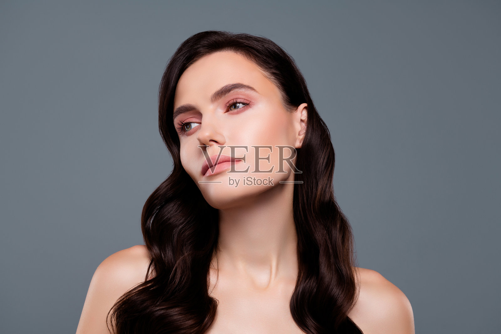 照片的白人妇女与黑发卷曲的头发看起来孤立的灰色背景照片摄影图片