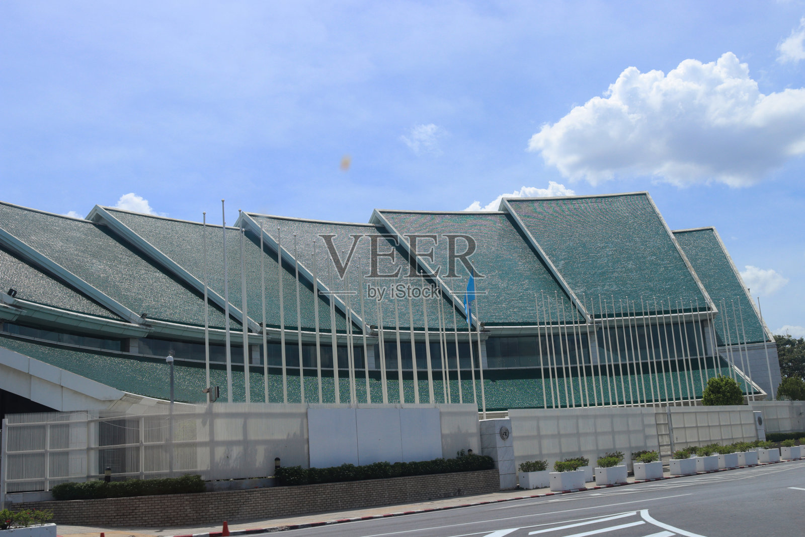 泰国曼谷,一个阳光明媚的日子,悬挂着国旗和棕榈树的联合国大楼照片摄影图片