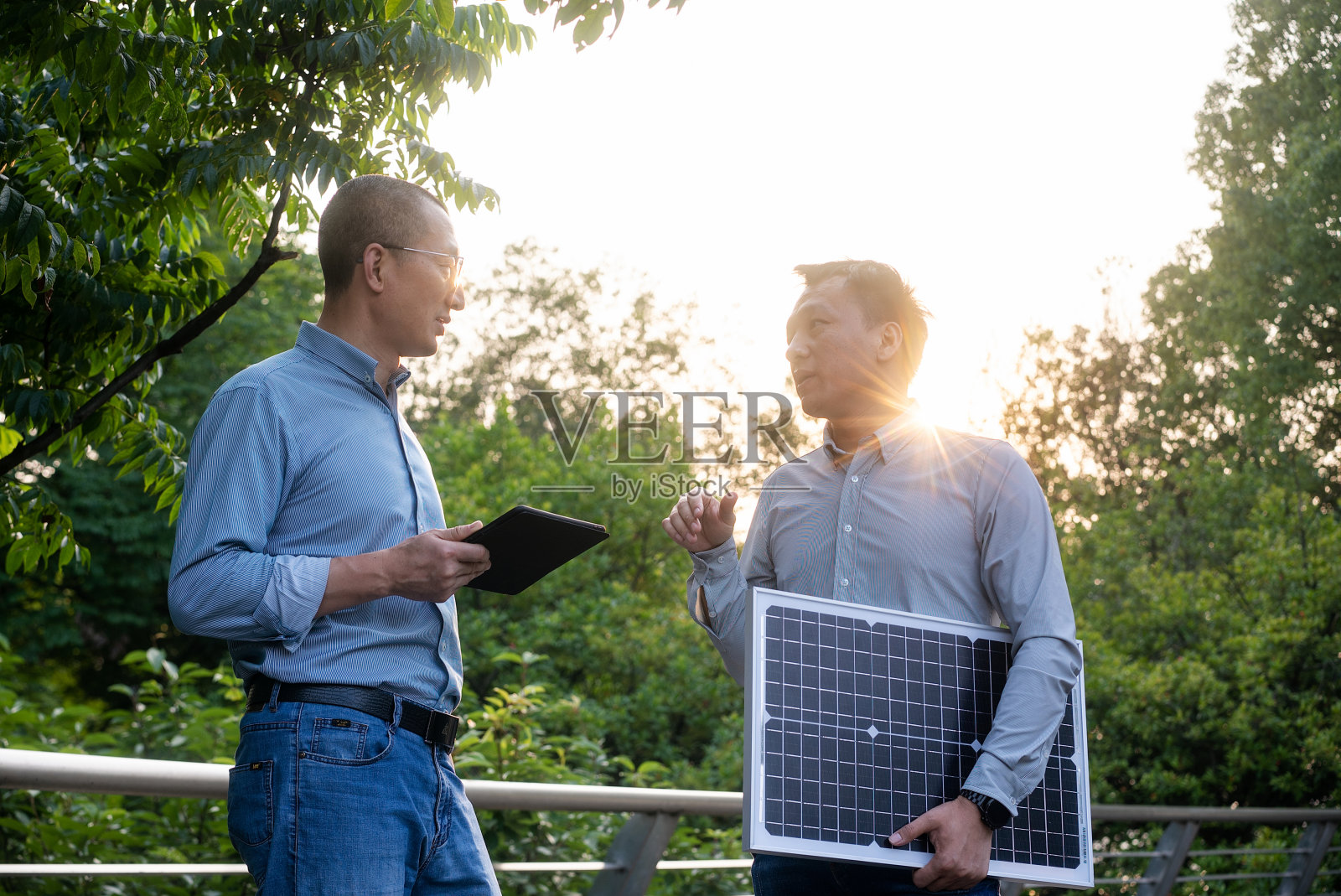 商务人士手拿太阳能电池板在天桥上沟通照片摄影图片
