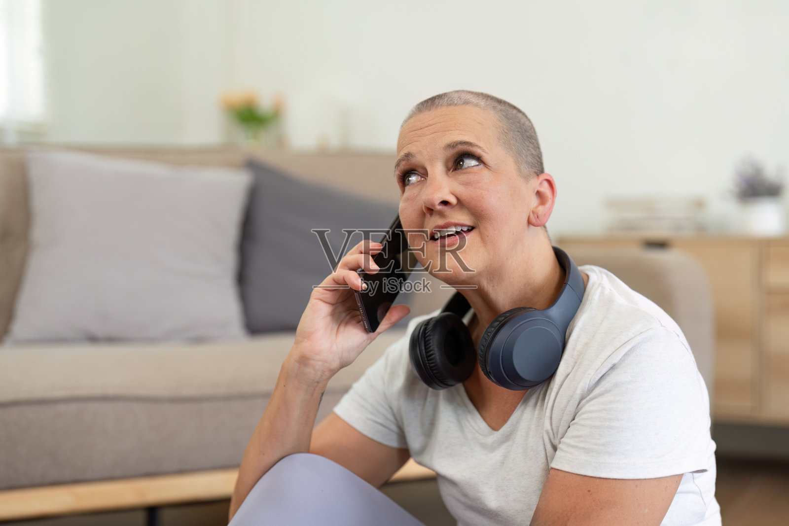 老年妇女在家边练瑜伽边用智能手机,拥抱现代科技和健康生活方式照片摄影图片