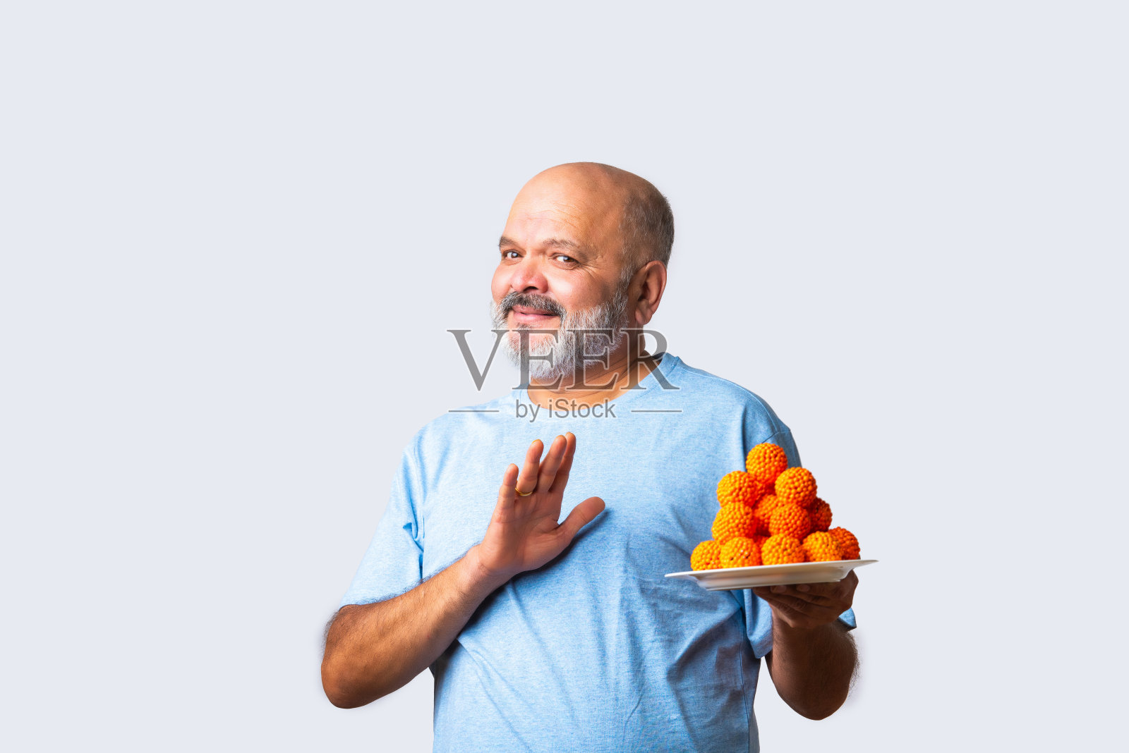 印度亚洲老年男子吃螺旋贾勒比或吉勒比或邦迪动力或拉杜在白色背景照片摄影图片