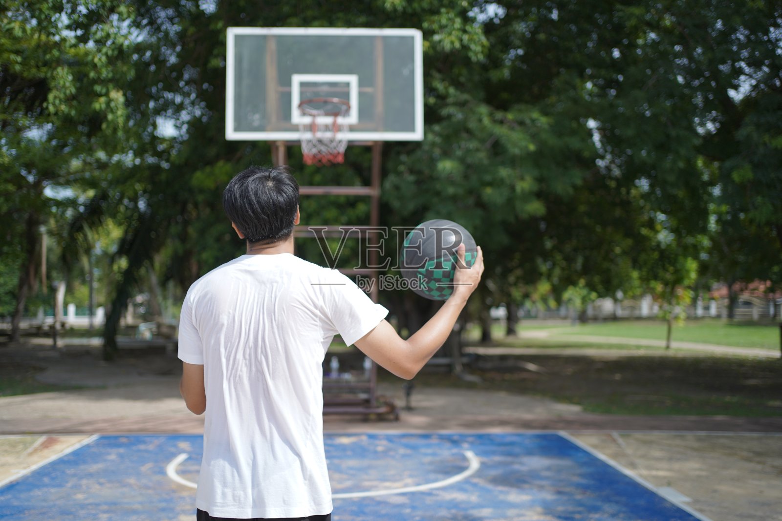 亚洲年轻人喜欢一个人在街头篮球场打篮球。照片摄影图片