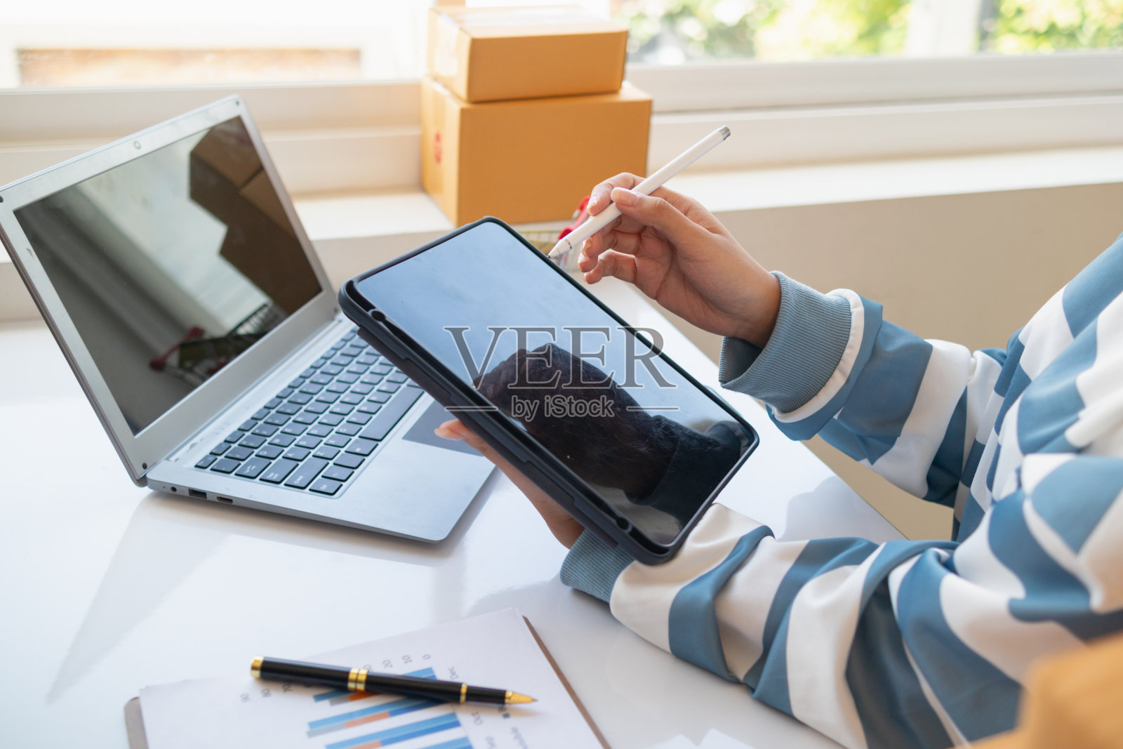 那些把自己的家当作办公室做生意,并通过网上申请销售产品的中小企业企业家正在检查产品库存,以确保它们足以满足订单。照片摄影图片