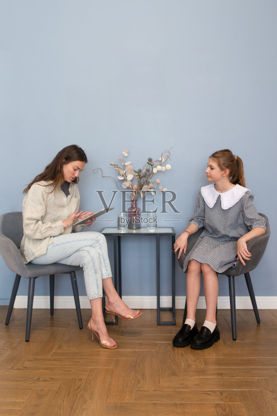 在学校办公室采访女学生。辅导员与学生谈话。一个社会工作者在学校和一个十几岁的女孩交谈照片摄影图片