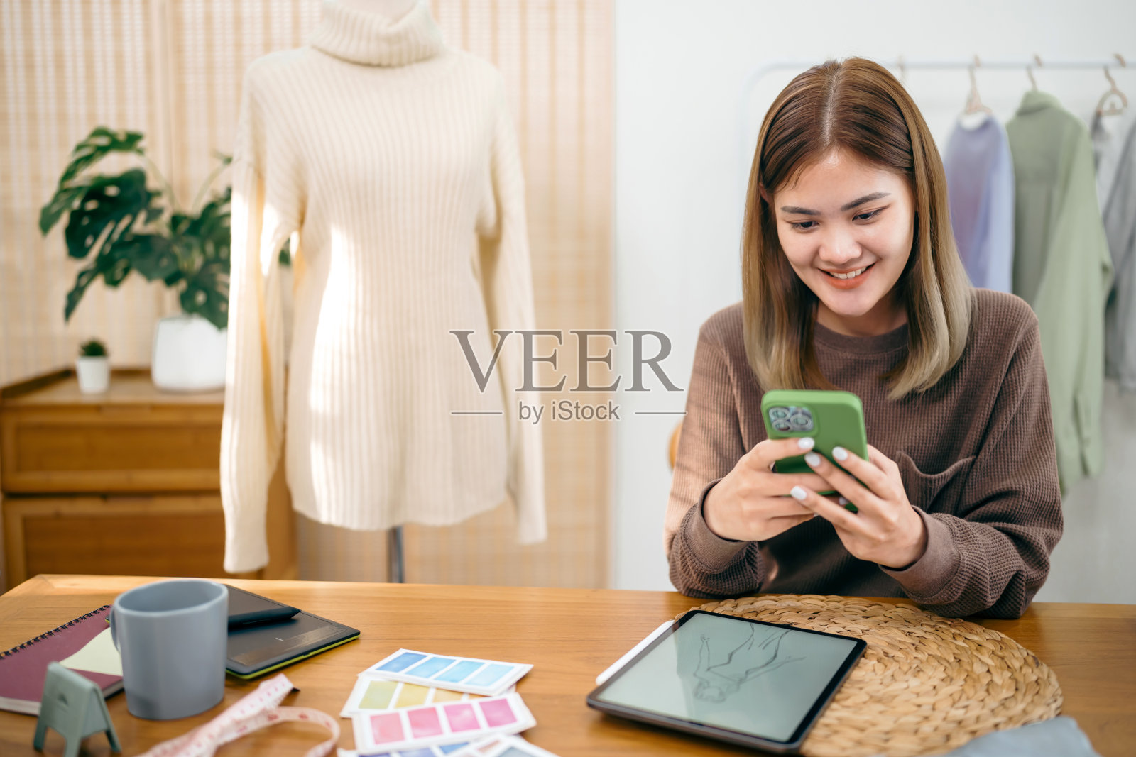 亚洲女性时装设计师时尚艺术家或创意设计师在草图上绘制新项目设计在工作室工作照片摄影图片