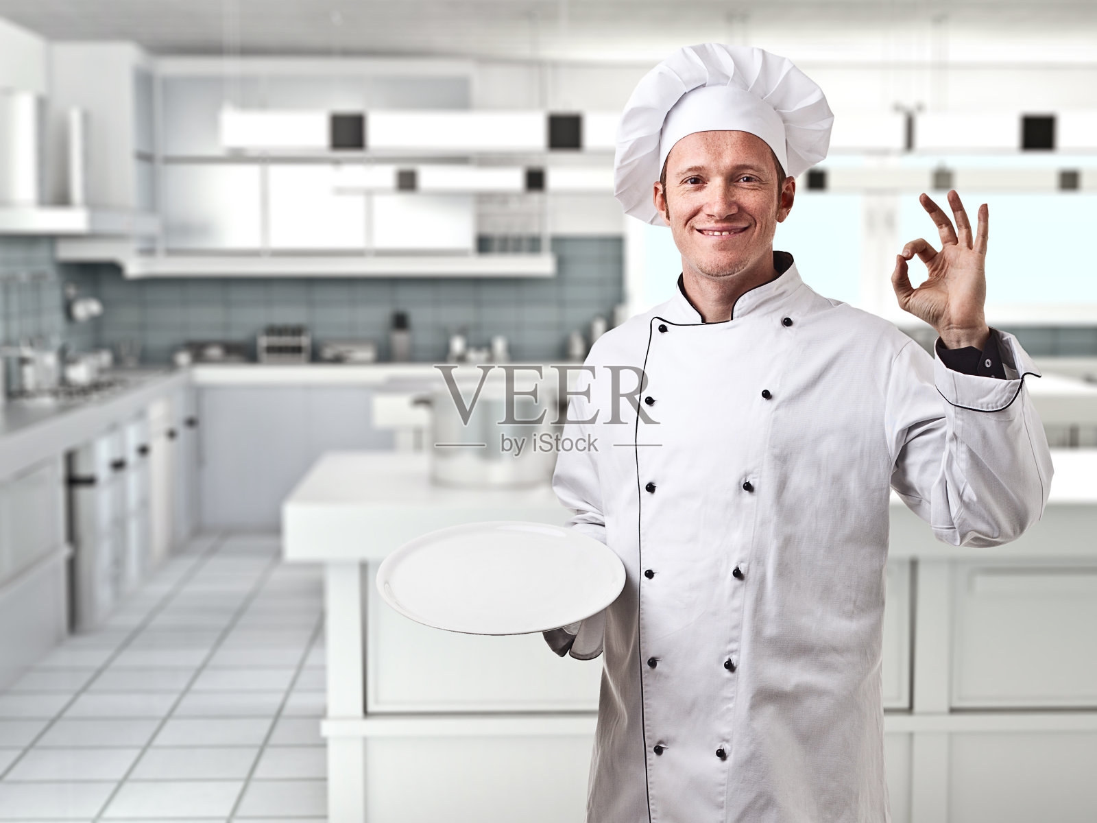 男厨师在厨房里微笑着做Ok手势的肖像照片摄影图片