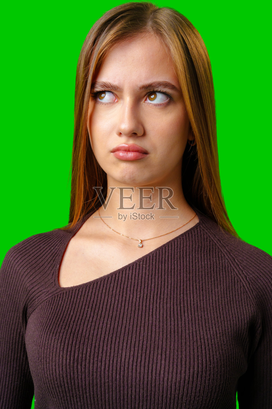 棕色头发穿棕色毛衣的年轻女子抬头看照片摄影图片