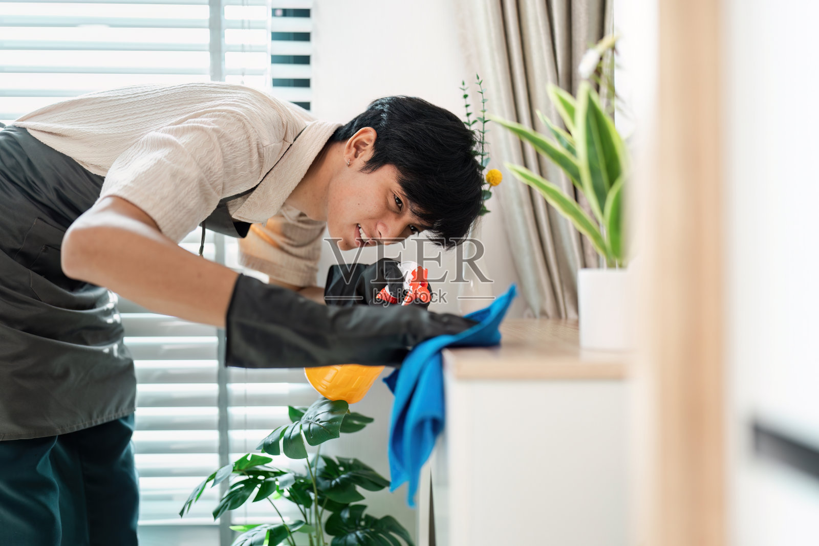 年轻人在明亮的现代客厅用喷雾瓶和布清洁室内照片摄影图片