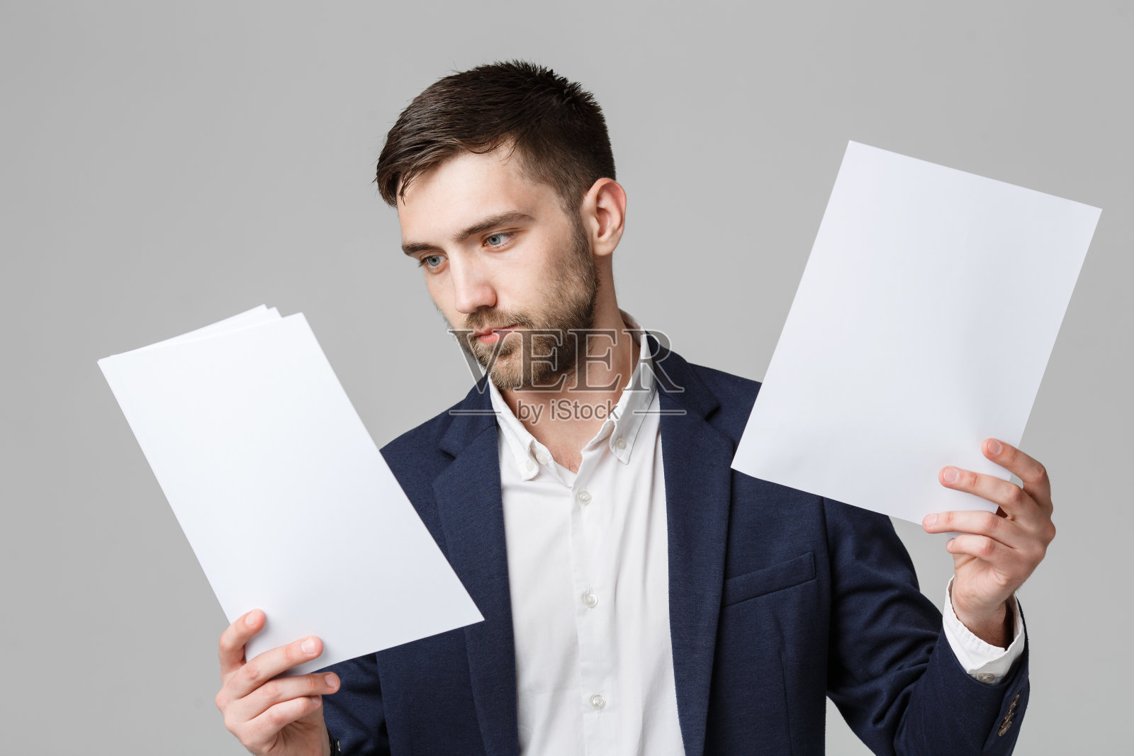 英俊的商人站在灰色的背景下检查文件照片摄影图片