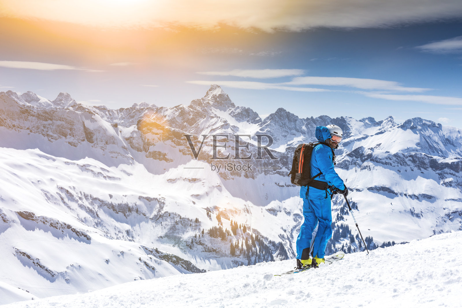 一个人站在白雪皑皑的山上,背对天空照片摄影图片