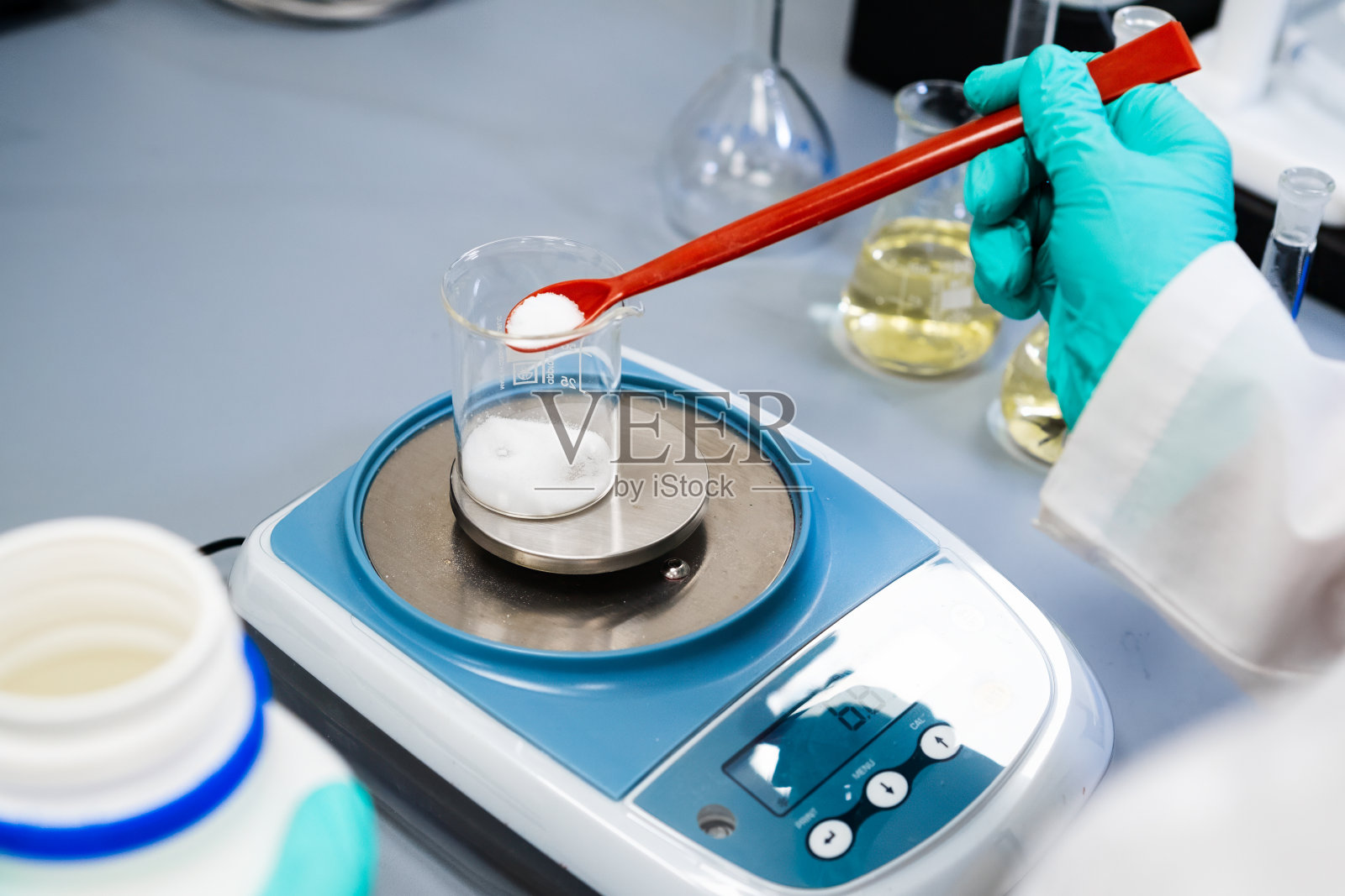 一位妇女用实验室天平称量粉末样品的特写。照片摄影图片