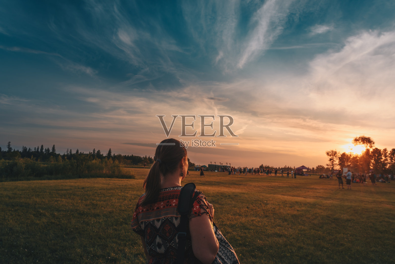 日落时女子在田野上对着天空的后视图照片摄影图片